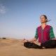 Young female practising yoga meditation on sand dune Jaisalmer, India
