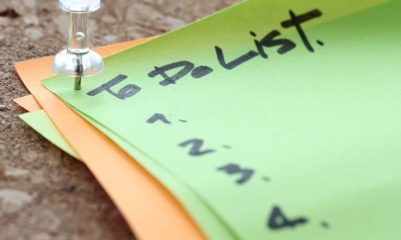 close up of pin and to do list word on sticky note with cork board as concept
