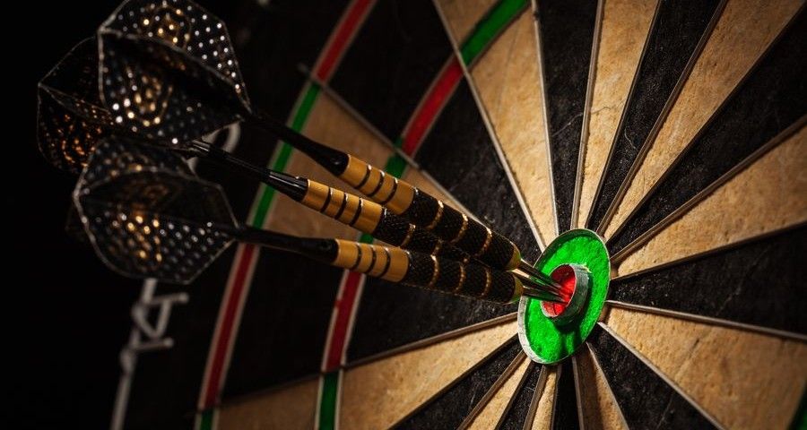 Success hitting target aim goal achievement concept background - three darts in bull's eye close up