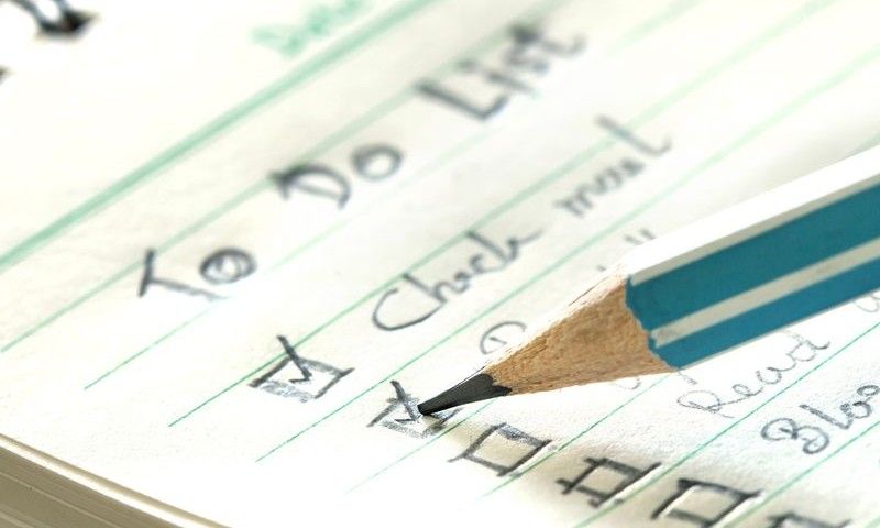 close up pencil checking on Handwritten to do list plan in the small note book
