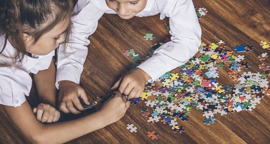 Happy boy and girl collect puzzle lying on the floor closeup