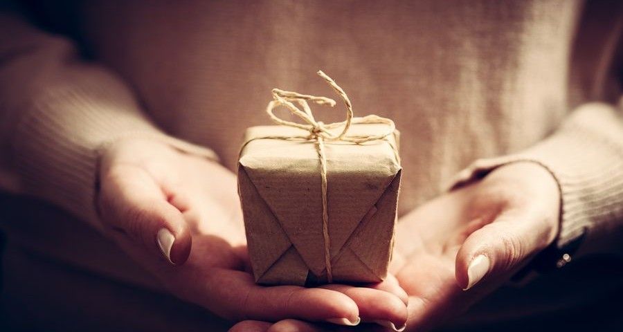 Giving a gift, handmade present wrapped in paper. Christmas time, vintage mood.