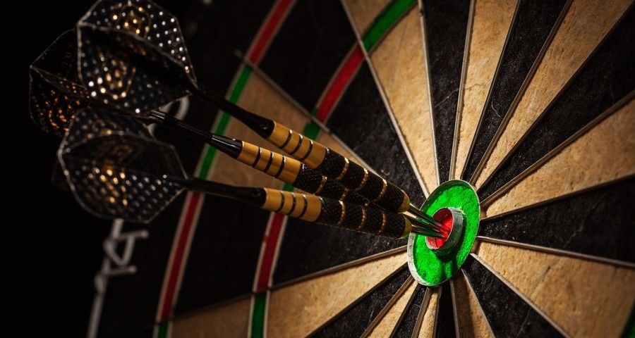 Success hitting target aim goal achievement concept background - three darts in bull's eye close up