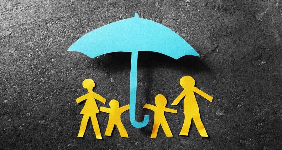 Paper cutout family of four under a blue paper umbrella