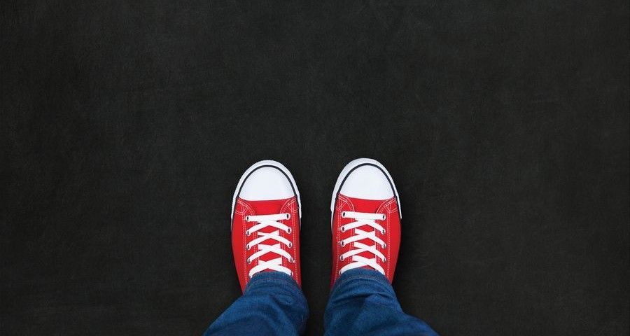 Feet wearing red shoes on black background with space for text