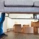 Close Up Of Man Carrying Sofa As He Moves Into New Home