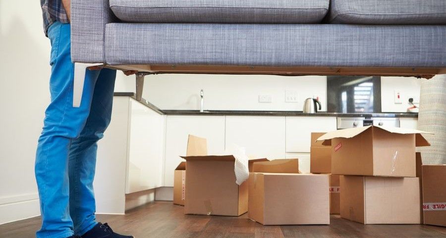Close Up Of Man Carrying Sofa As He Moves Into New Home