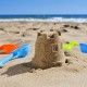 a sandcastle and toy shovels on the sand of a beach